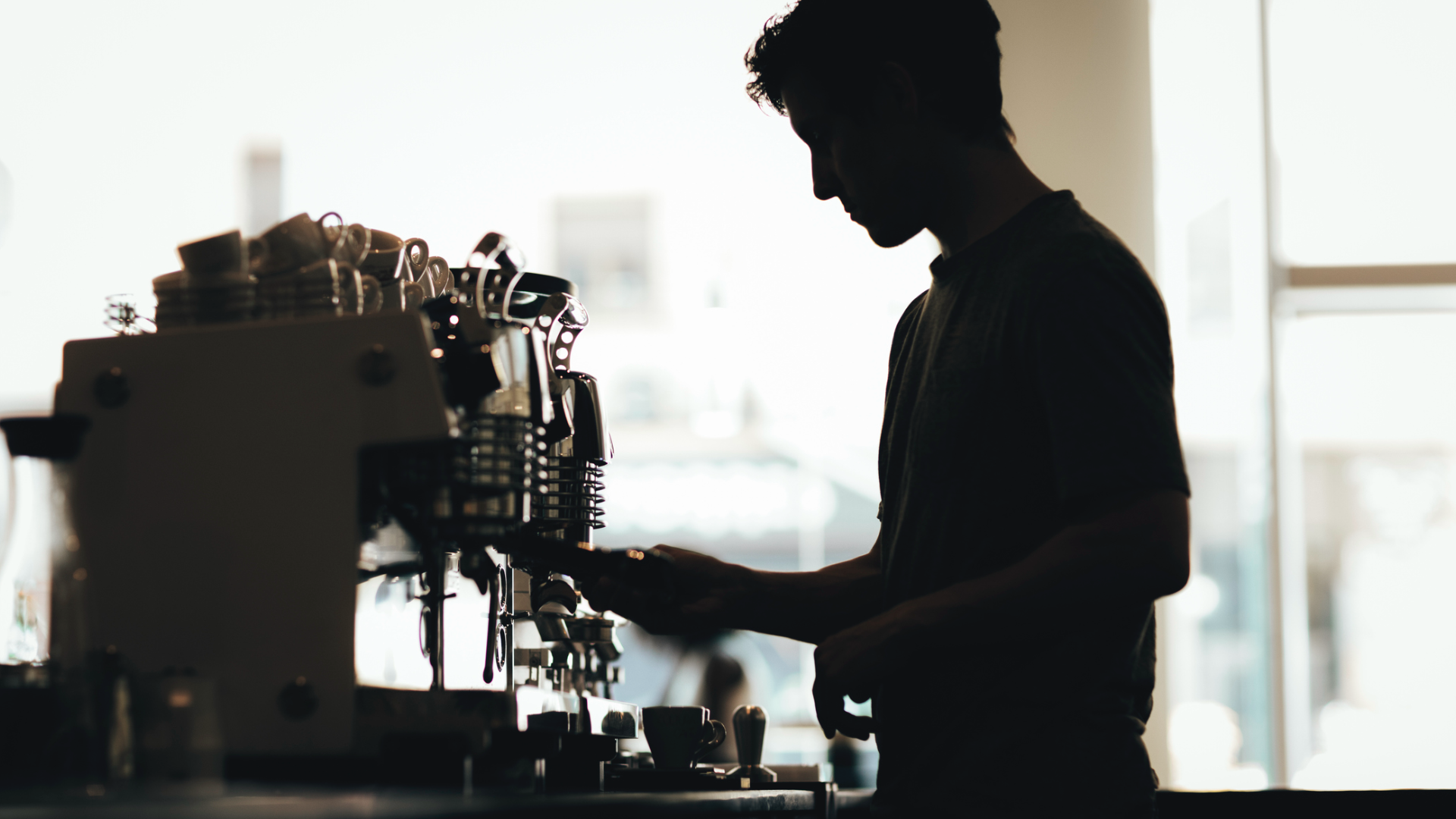 silhueta de um homem mexendo em uma máquina de café